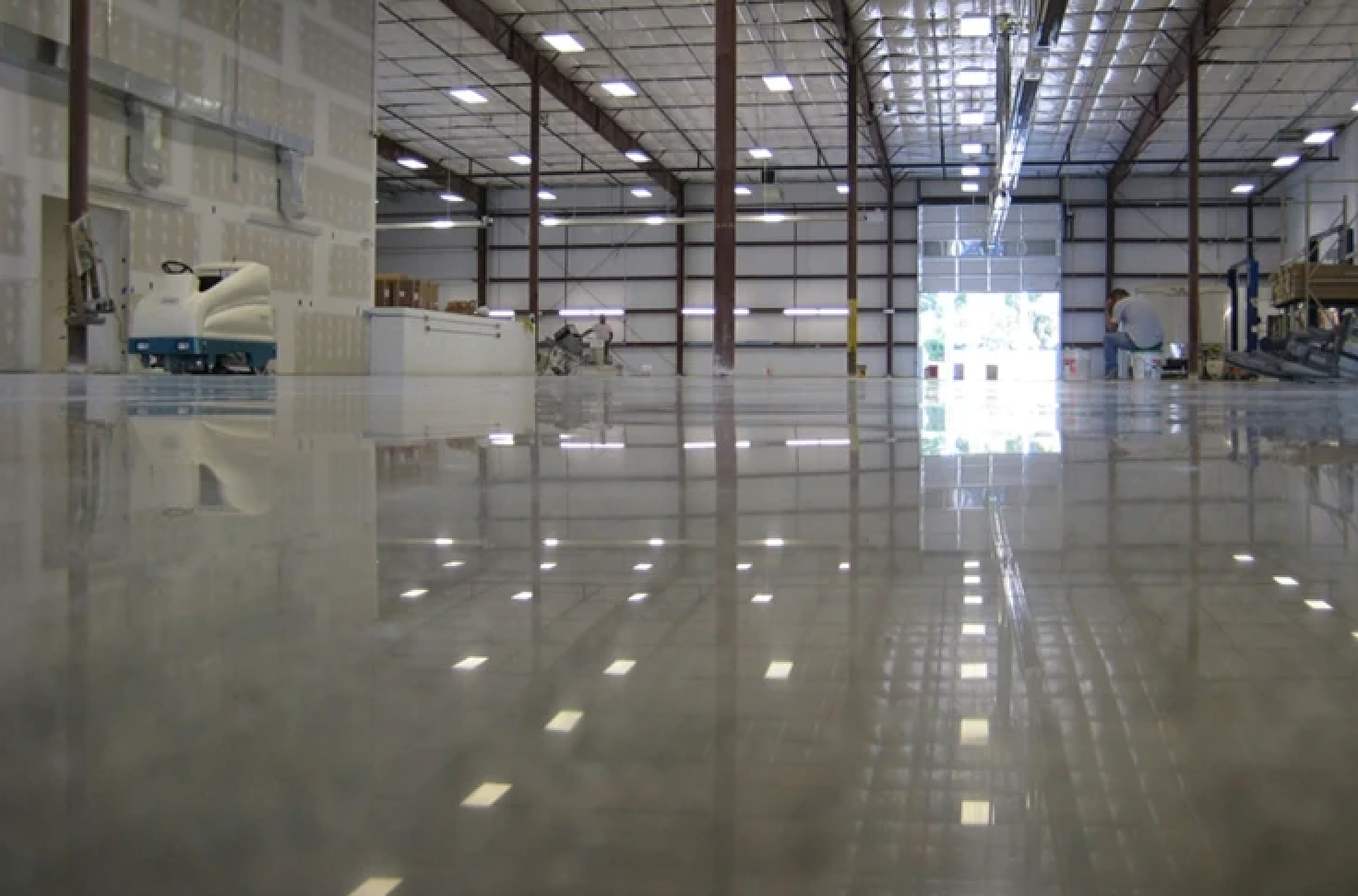 inside of large warehouse with gray epoxy floors, light on ceiling.