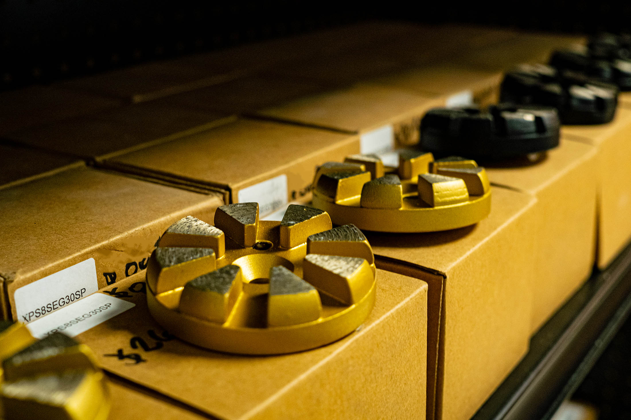 Gold and black floor grinding metal rounds in a row on cardboard packaging 