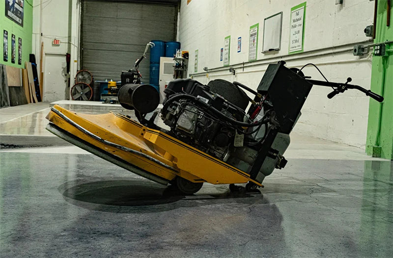 Yellow and black concrete flooring machine sitting at an angle inside warehouse 