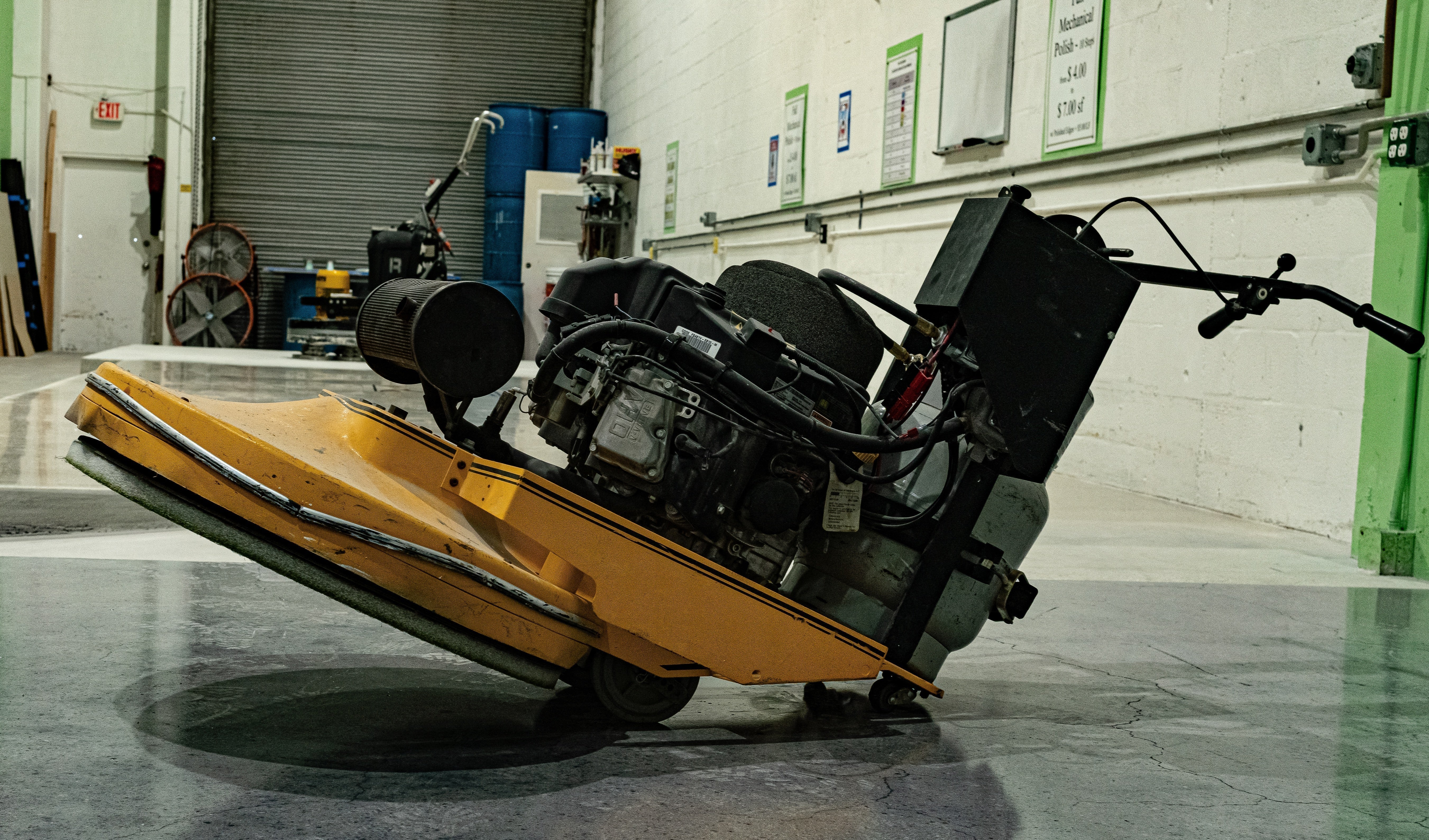 An epoxy and concrete industrial floor grinder posed for display in a warehouse setting.