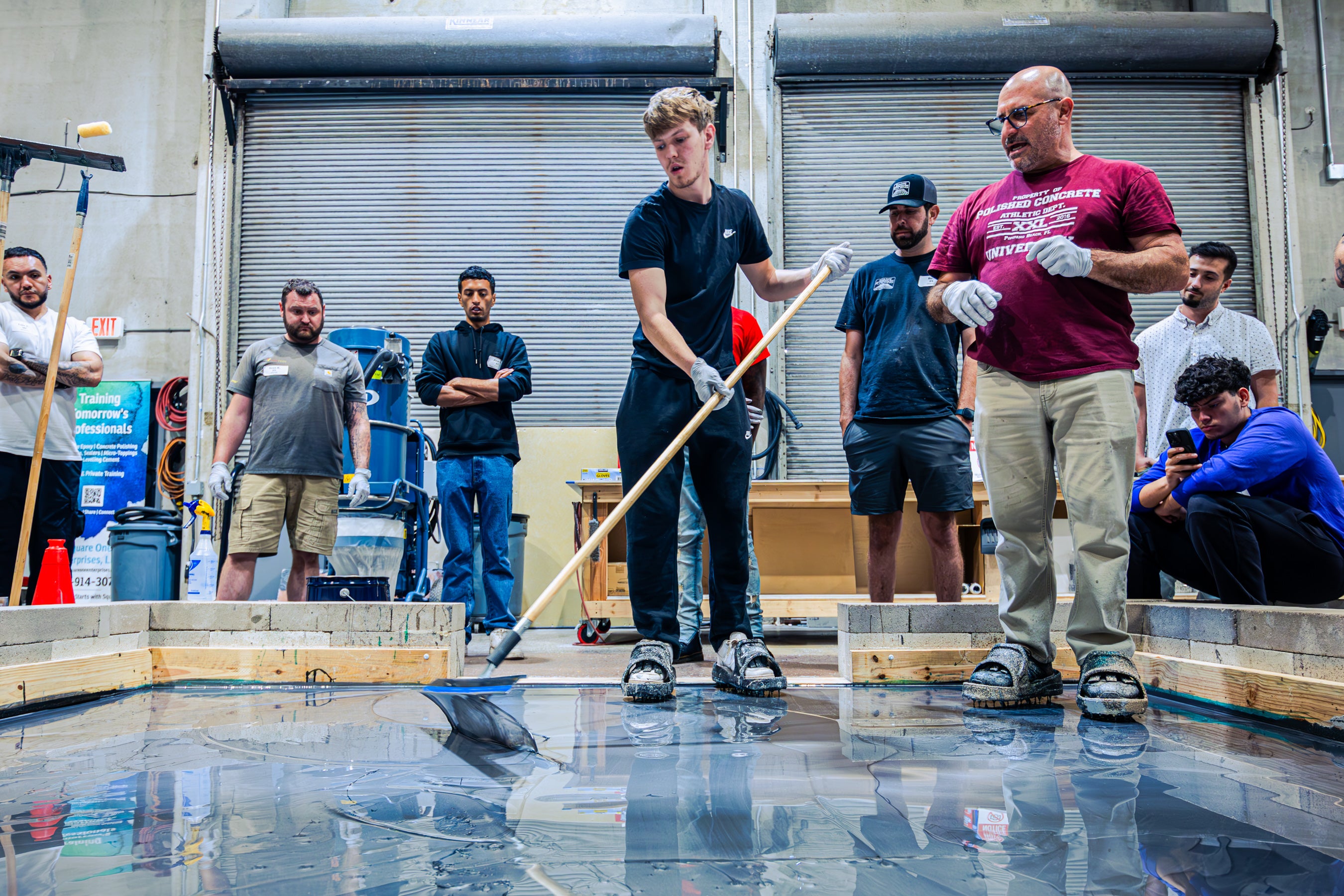 Group of students learning epoxy flooring application and tools 