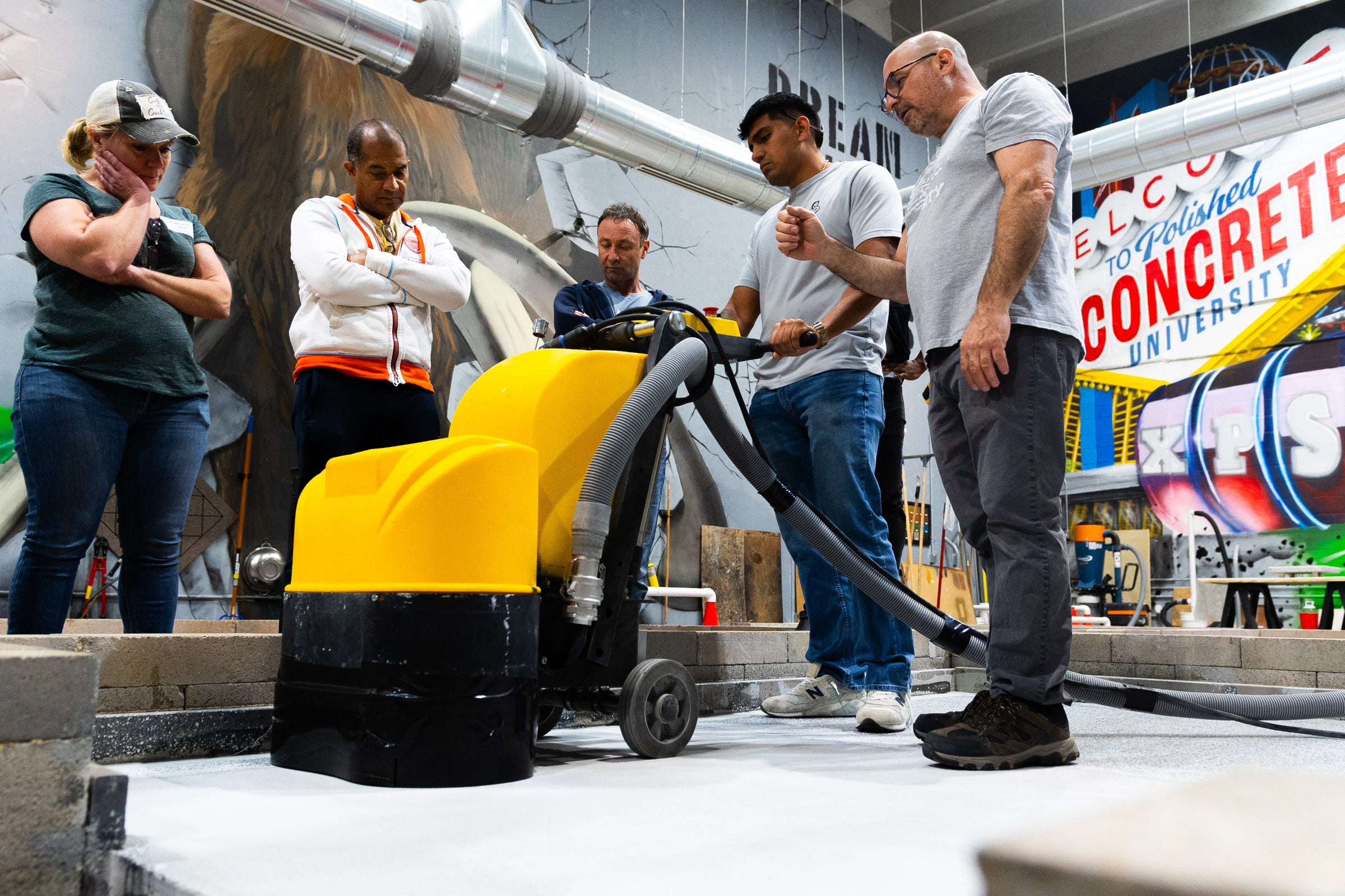 Group of students around a Concrete Genie polishing machine in an XPS training course