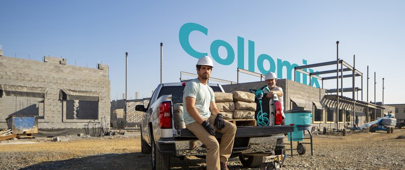 construction men on job site with pickup truck filled with material, Collomix logo in background