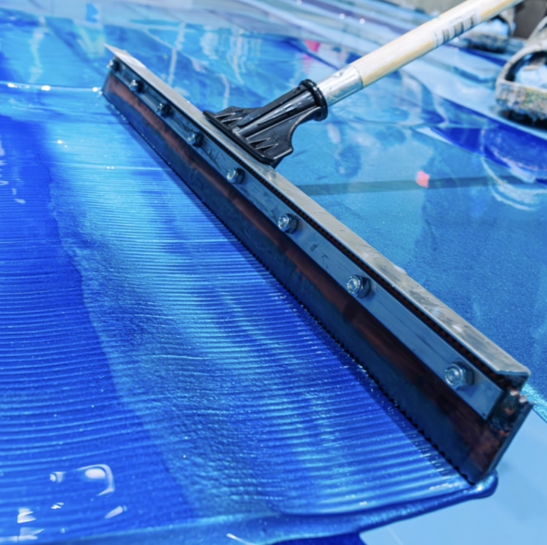 Squeegee on bright blue metallic floor.