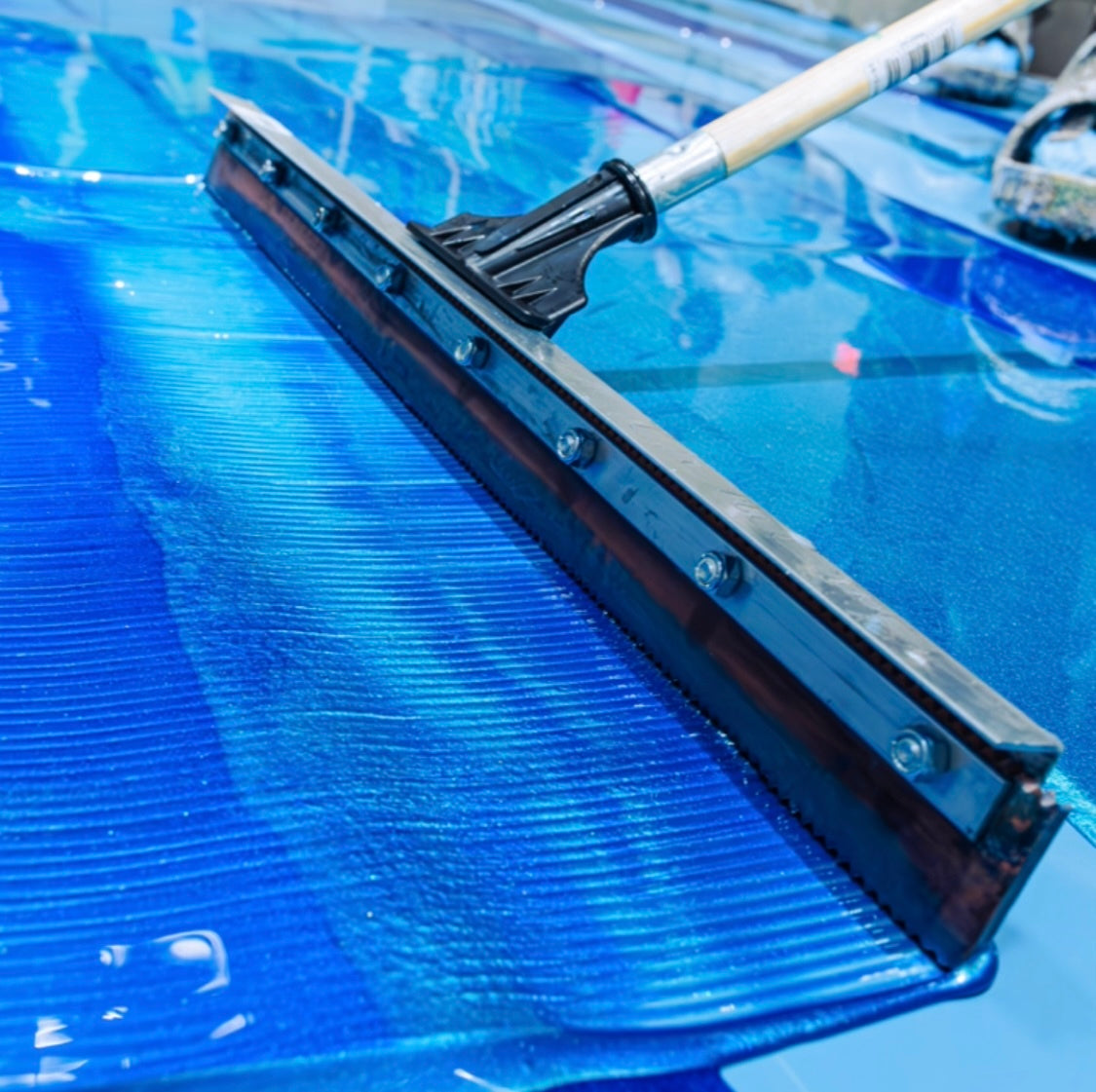 Squeegee on bright blue metallic floor: Epoxy Flooring Toronto, Epoxy Canada, and Flake Epoxy Flooring.