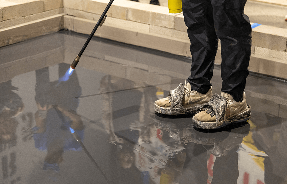 Torch being used on an epoxy floor to minimize bubbles. Epoxy shoes or epoxy spiked shoes for epoxy application. 