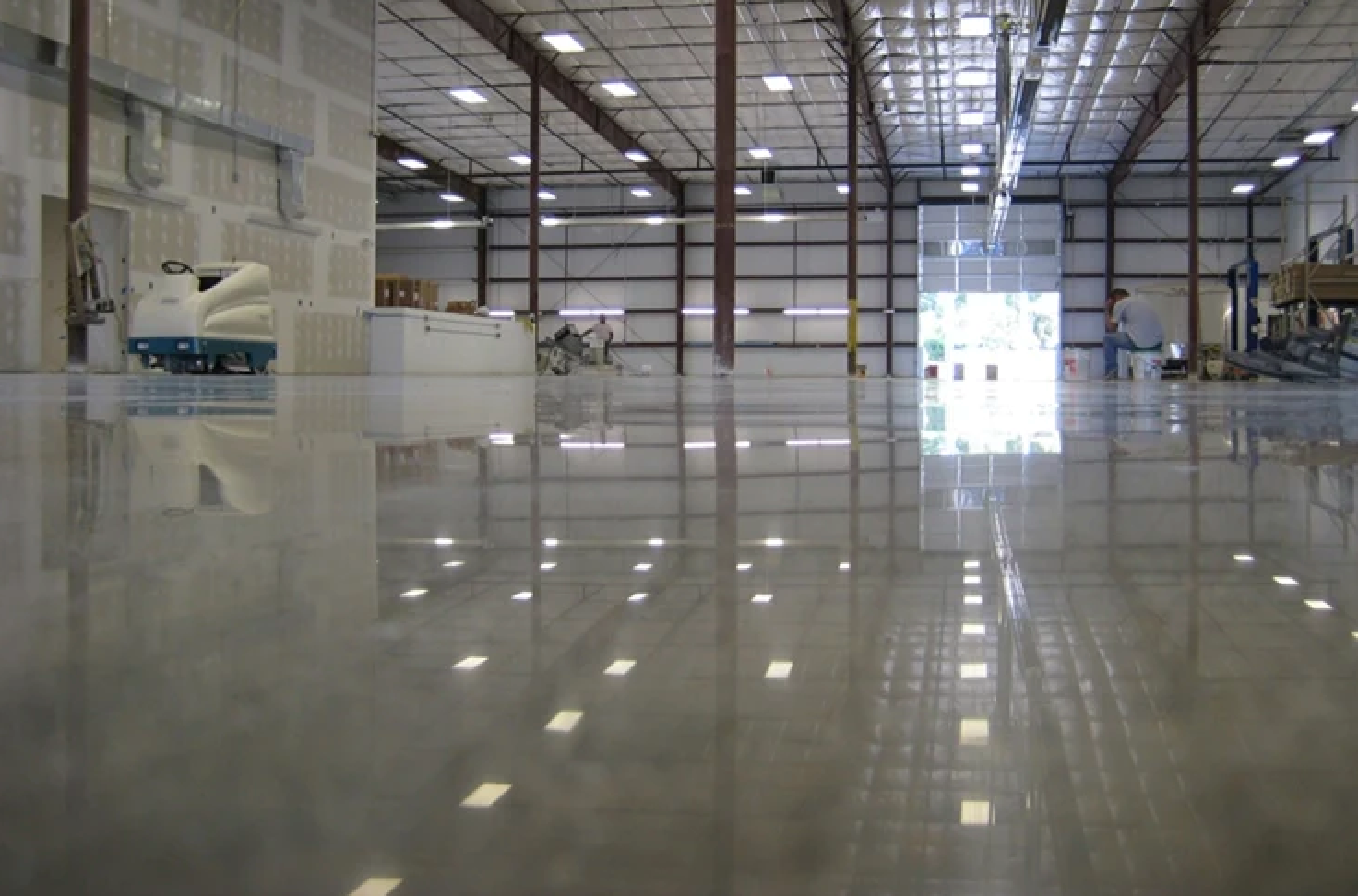 inside of large warehouse with gray epoxy floors, light on ceiling. 